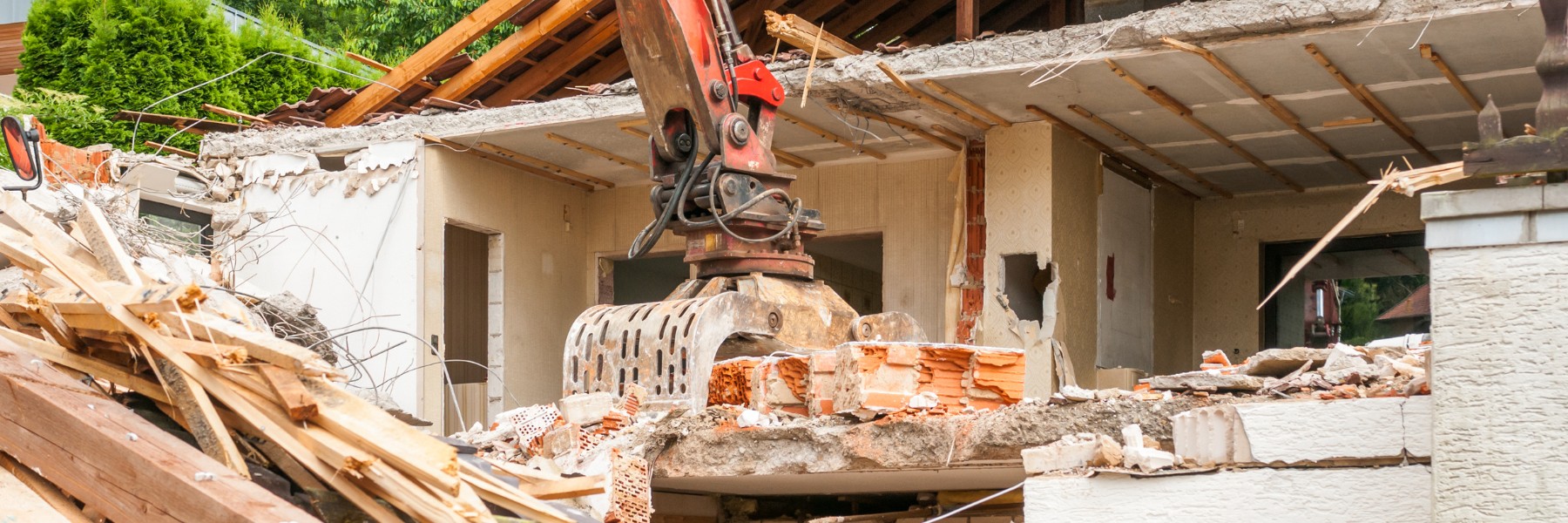 Excavator tearing down an old house