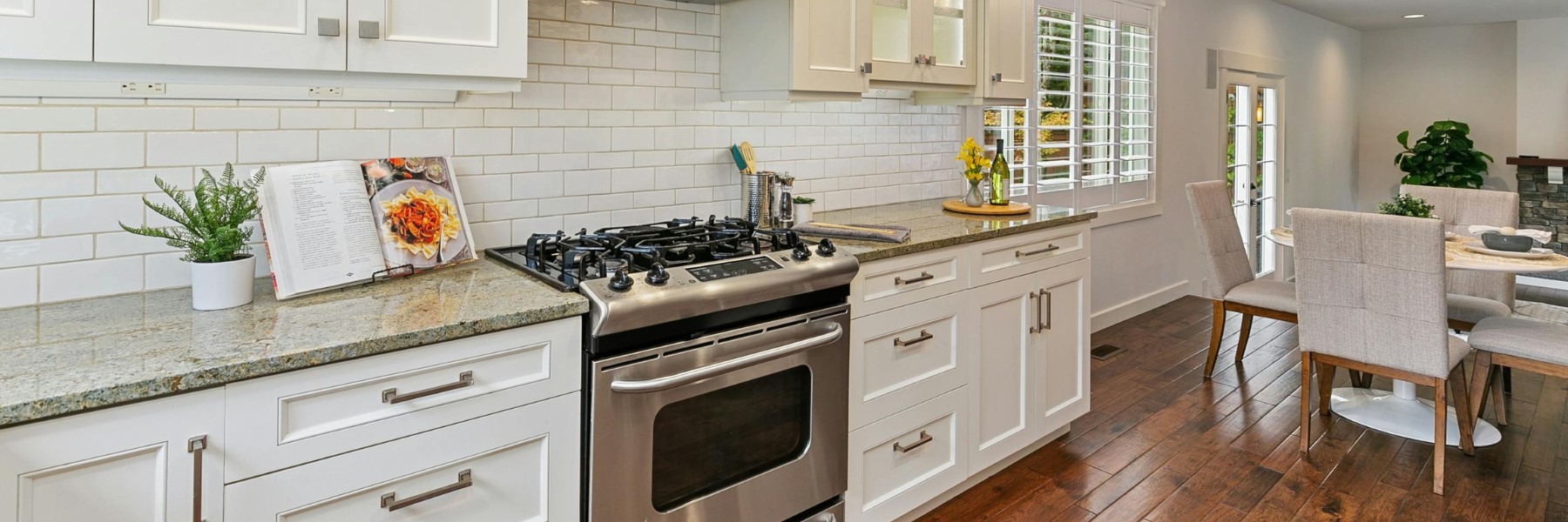 Bright white kitchen with granite countertops and stainless range