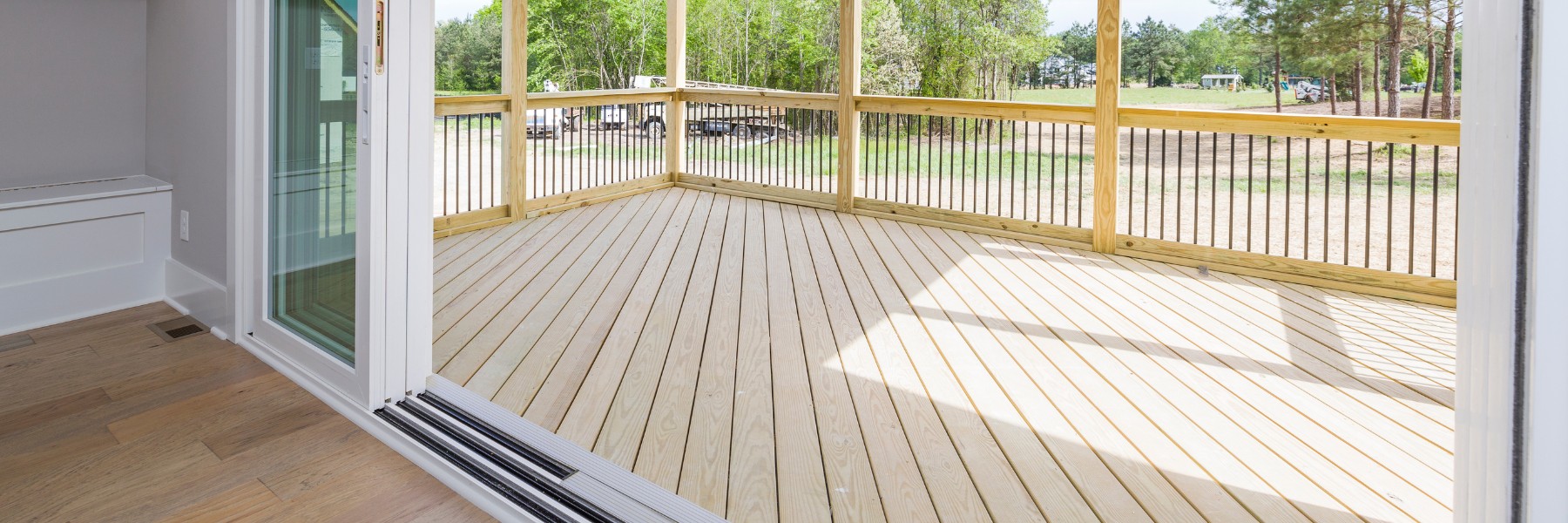 Wood deck with railing seen through open sliding doors
